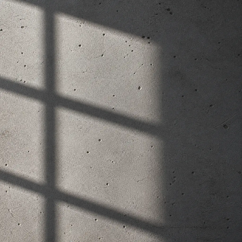 Rough grey concrete with fine pores and a geometric window shadow in side light