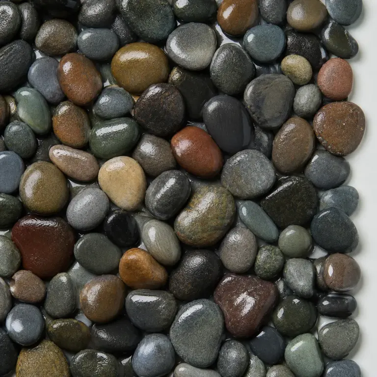 Top-down texture of rounded wet multicolor pebbles with 45-degree side light and a visible outer edge